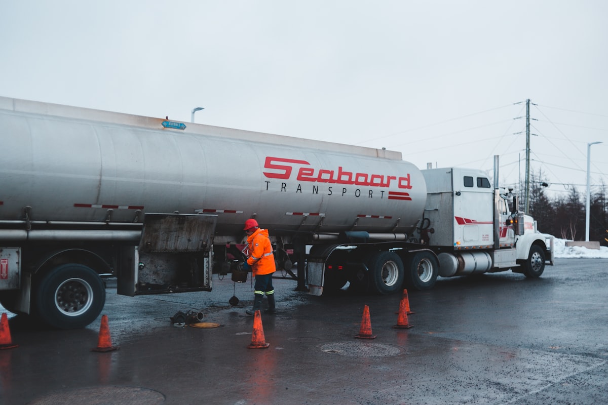 Fuel tanker truck being refueled by an attendant in North America.