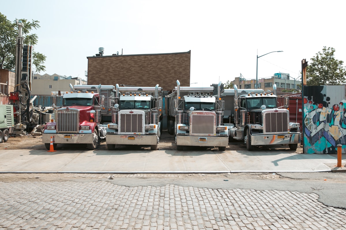 Row of American Peterbilt Class-8 tractors parked at a US carrier yard.